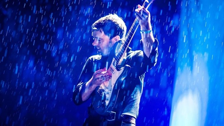 雨の中ギターを弾く男性